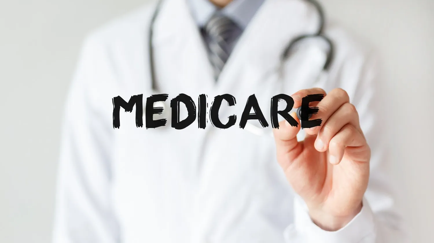 A doctor writing the word Medicare on a clear board